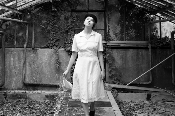 Das Taschentuch im Film - eine junge Frau im Stil der 1940er Jahre ist verträumt mit ihrem Taschentuch in einem Gewächshaus spazieren