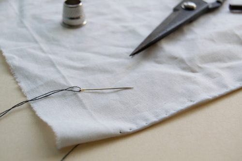 Fertiger Rollsaum von der rechten Seite Detailaufnahme von Nähnadel, Fingerhut und Zuschneideschere